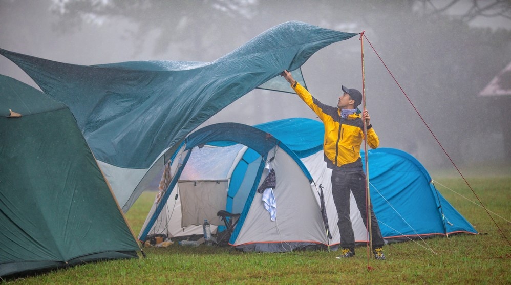 a man fixing a tent while raining