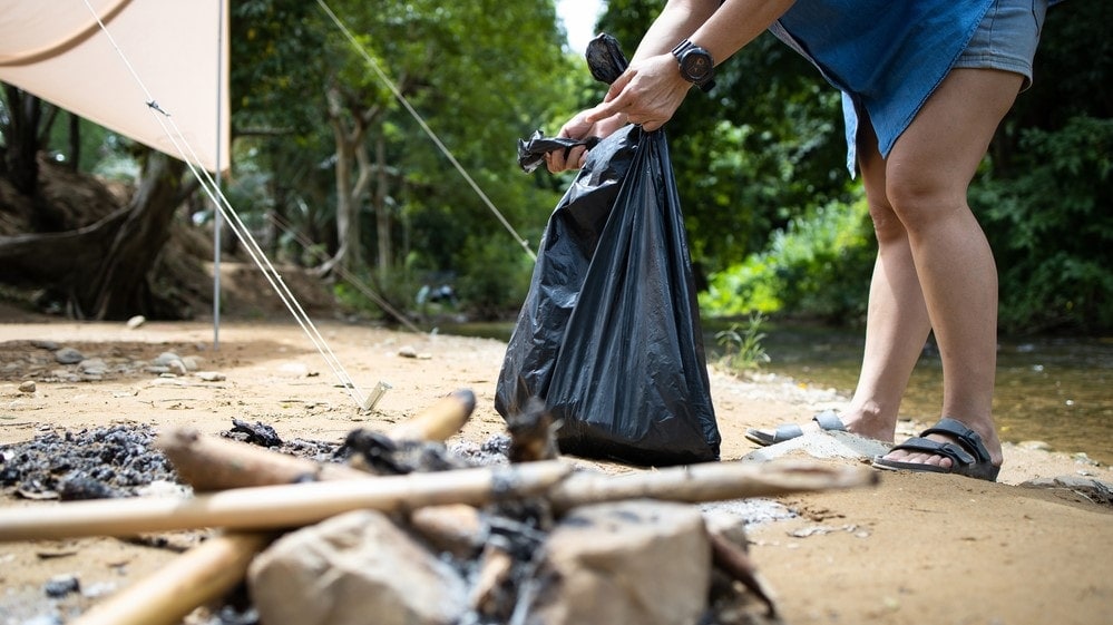 a woman cleaning up the garbage during camping