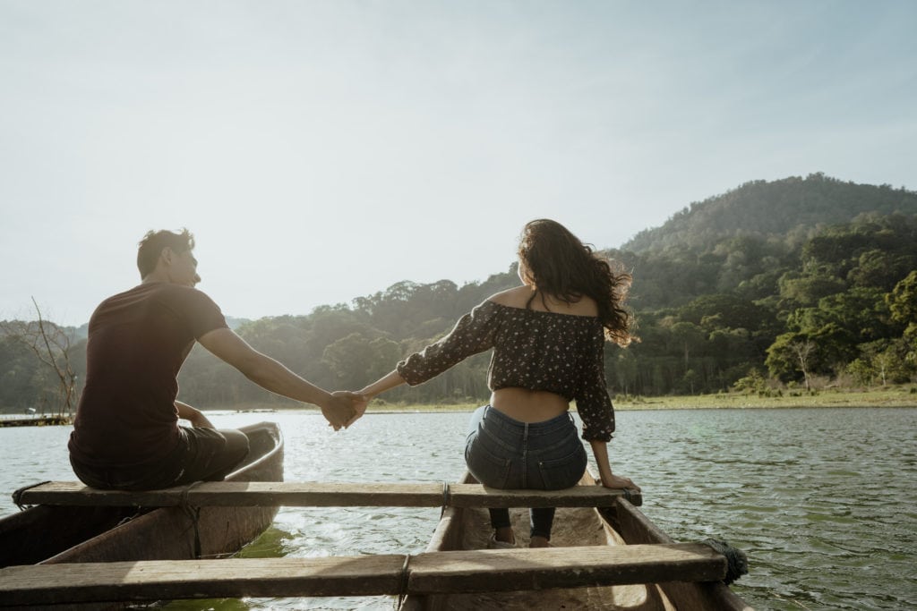 A canoe date in the lake with the couple holding hands