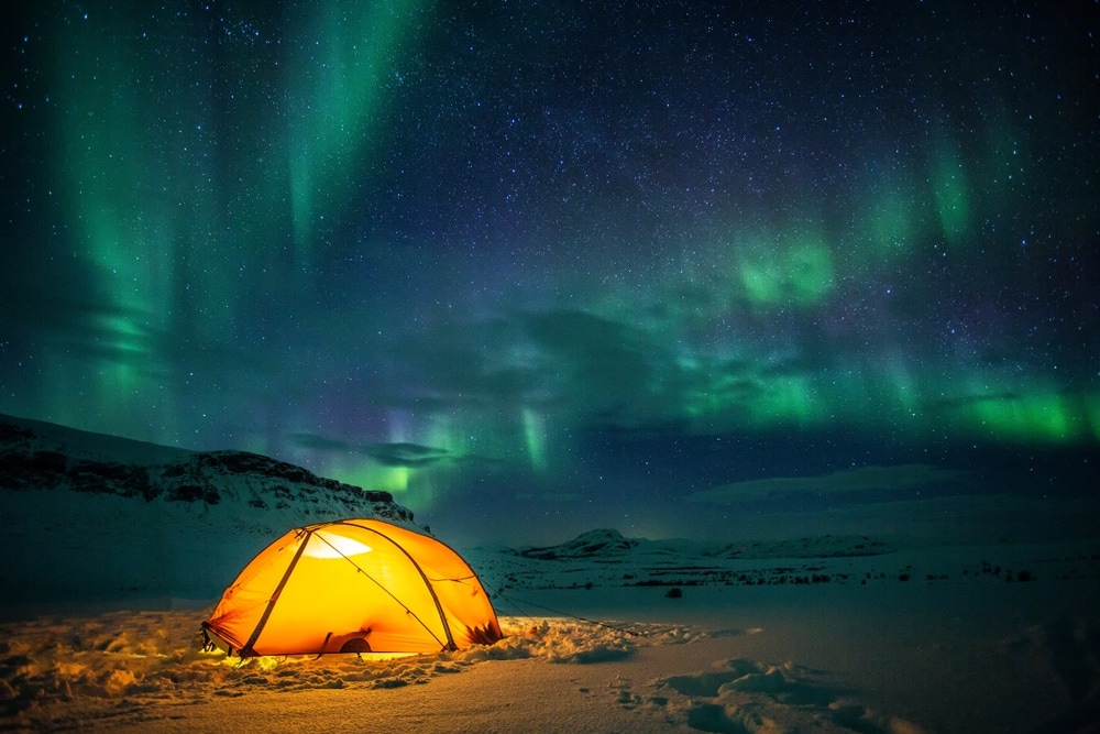 image of a tent under Aurora Borealis during winter