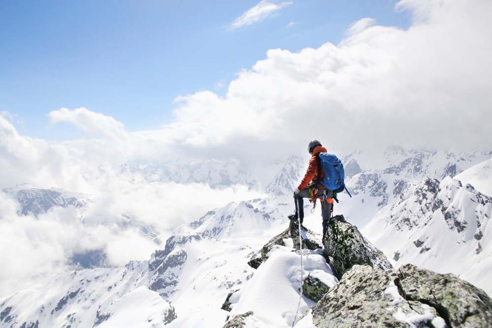 Person mountaineering at the top of a mountain covered in snow