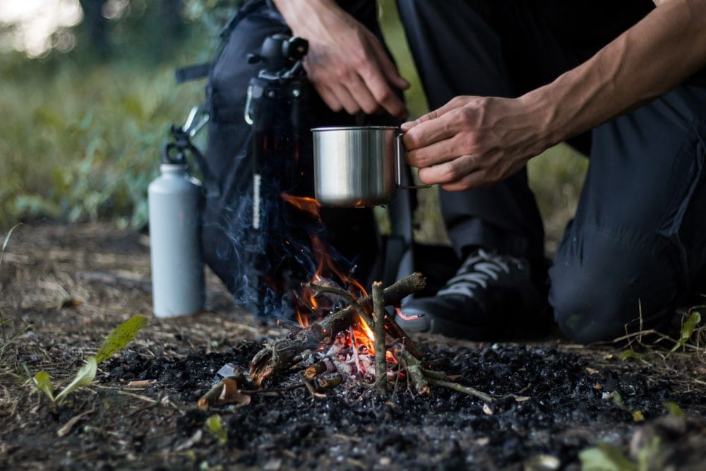 Survivalist in nature cooking on fire