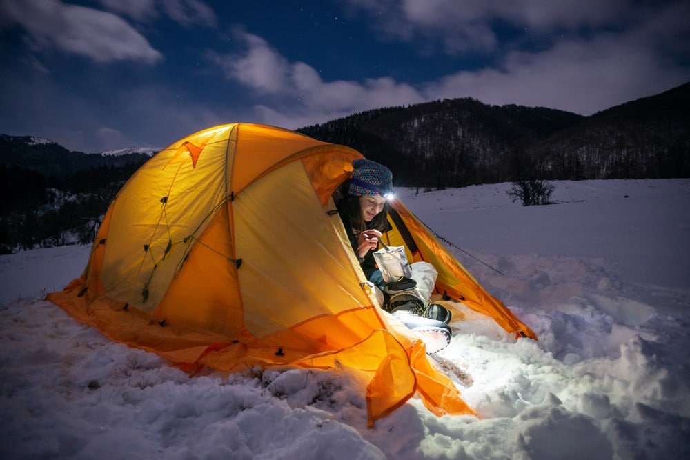 Person camping in the snow during winter camping