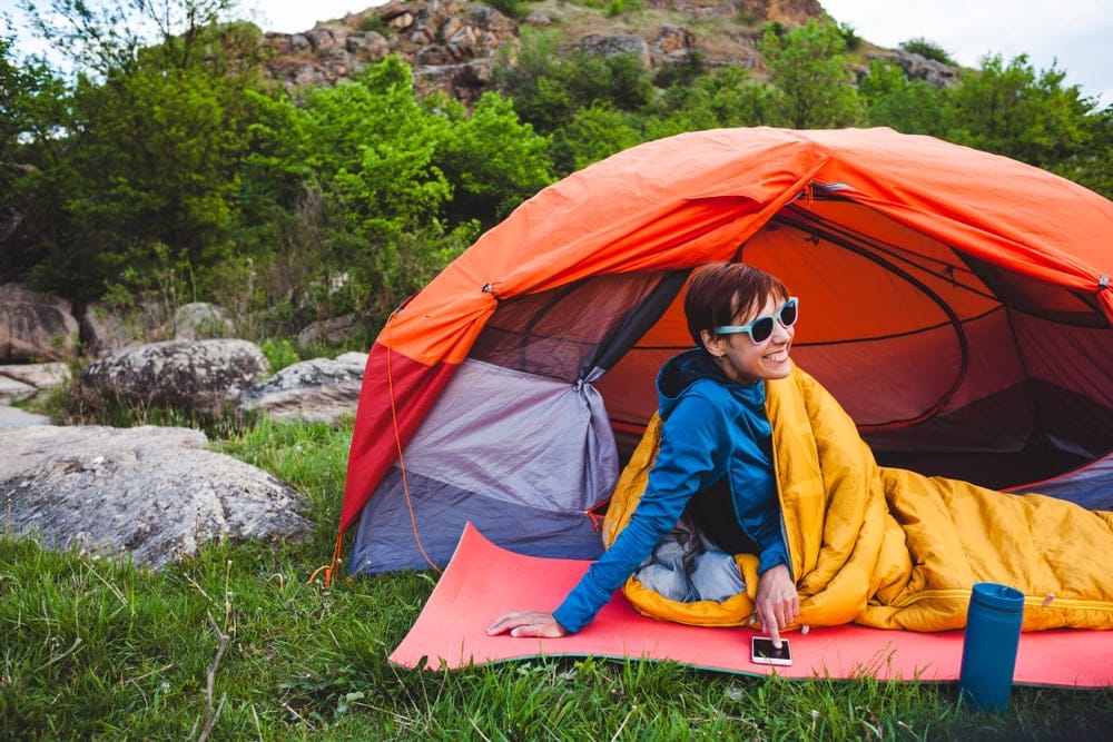 Woman wearing shades looking comfortable beside her tent