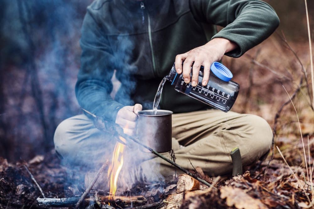 Man pouring water to a camping mug