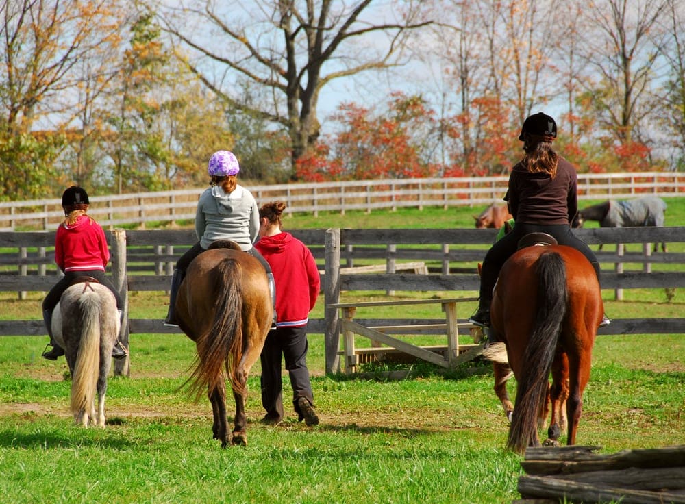 Kids riding horses on a campground
