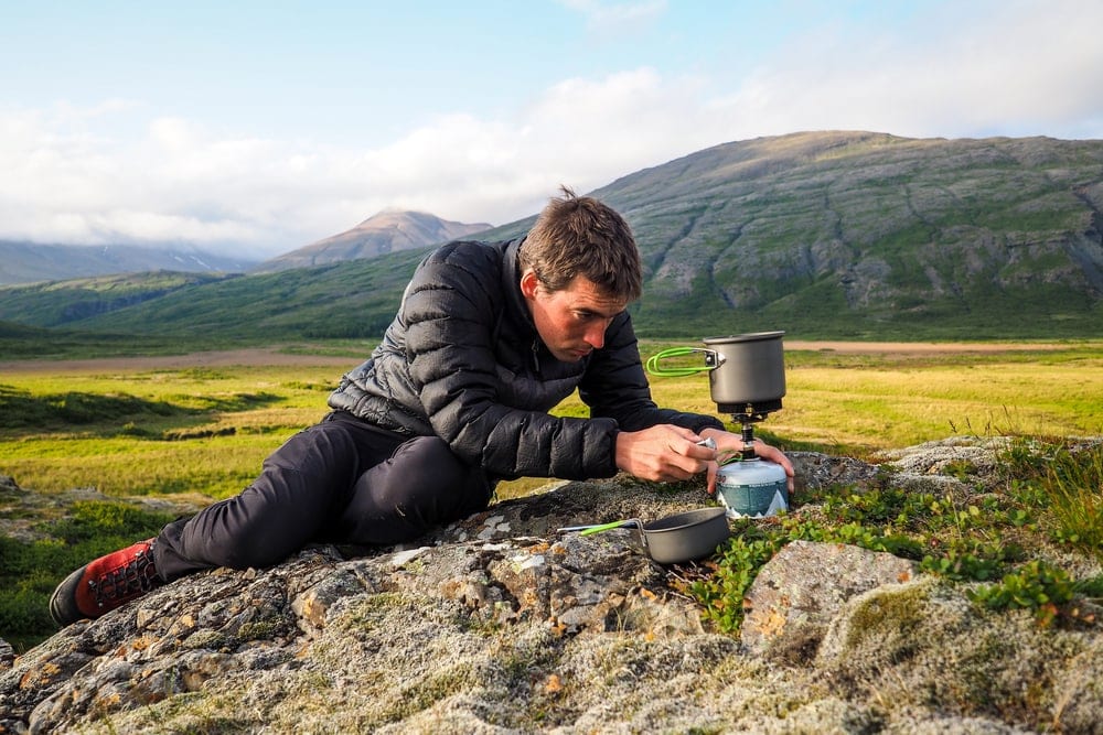 Man trying to use a canister stove to boil water while camping