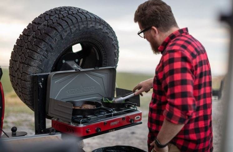 Man cooking using a camping propane stove
