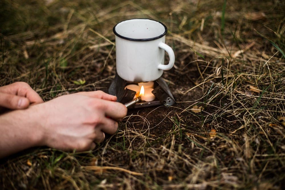 Person lighting up a solid fuel stove to boil water while camping