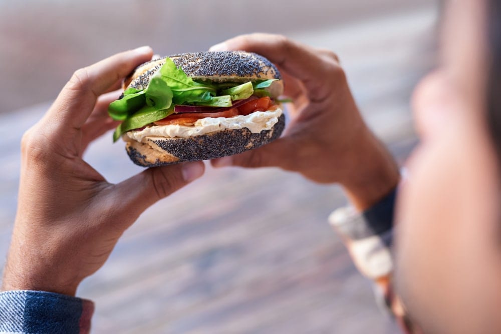 A person holding a bagel as camping snack