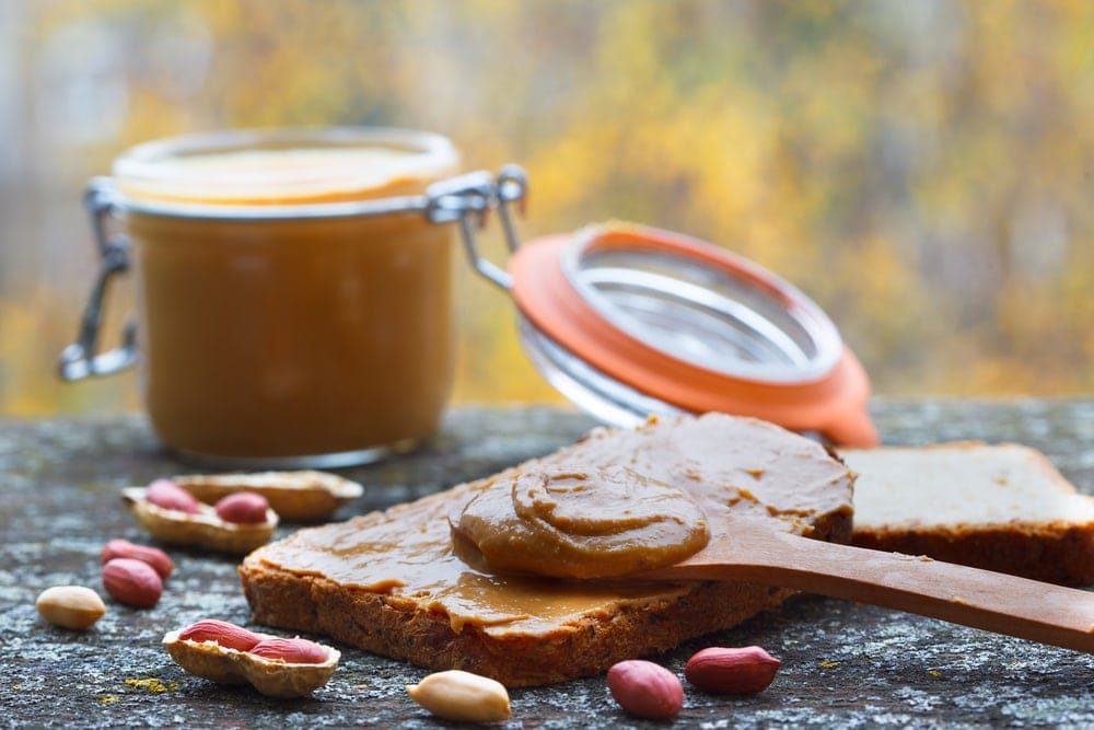 Peanut butter on bread with a butter jar behind for camping food