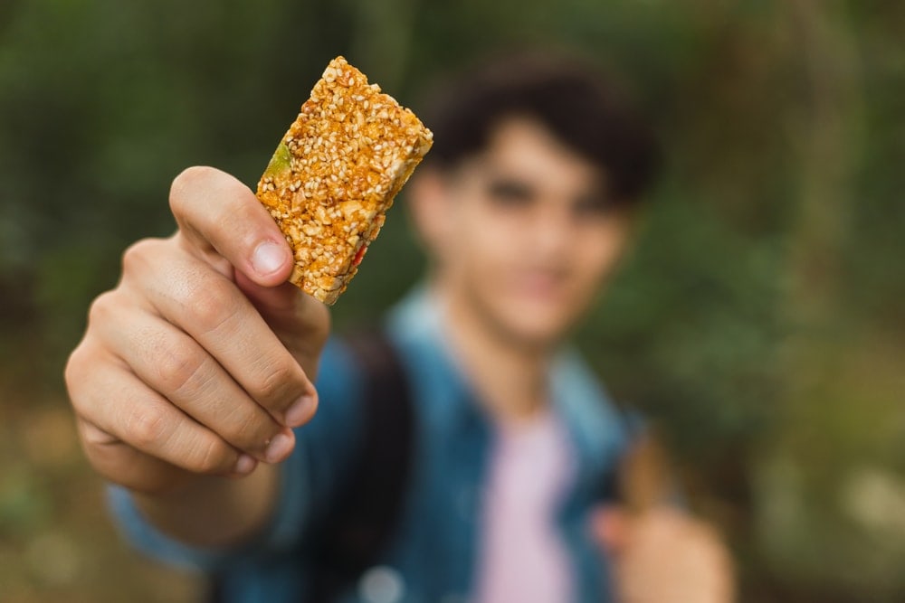 Man holding a granola bar as camping food