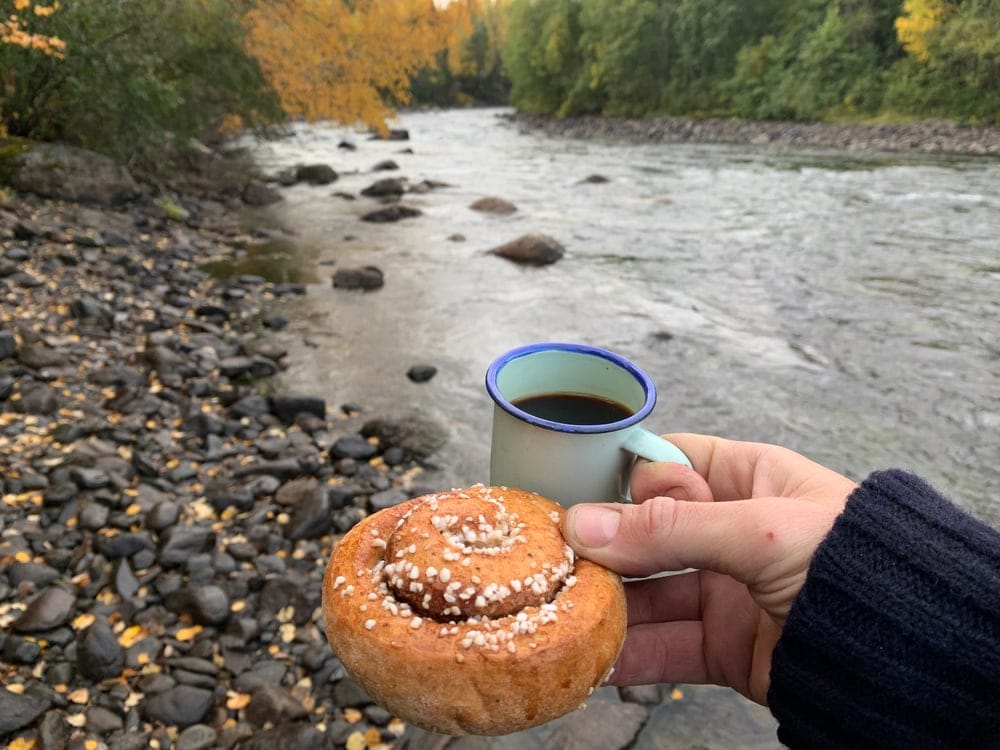 A camper holding a cup and a cinnamon as camping food