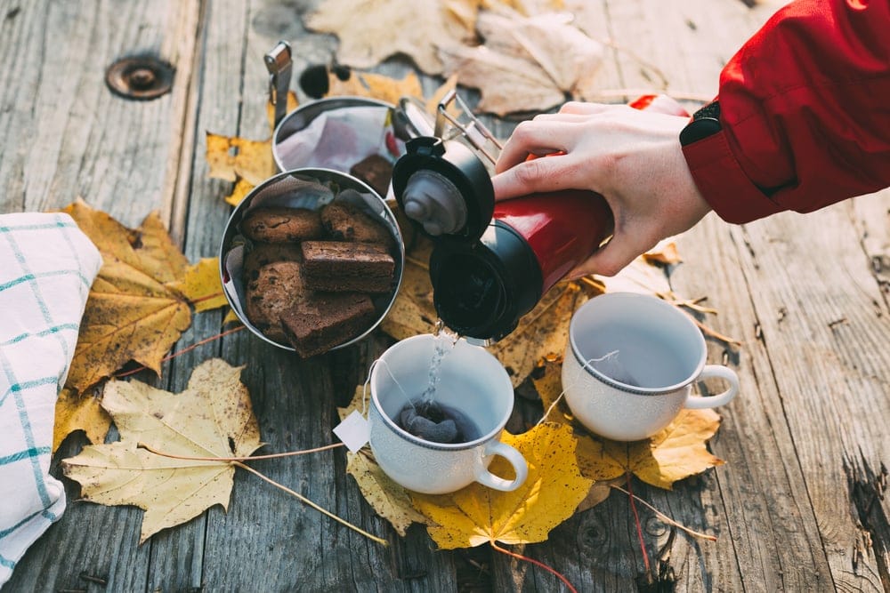 Camper pouring a water to a cup and with brownies beside as camping food