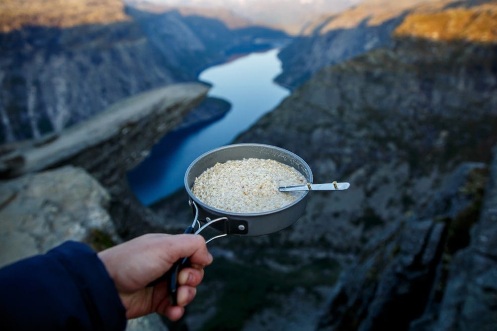 A hand holding a pan with oatmeal while camping