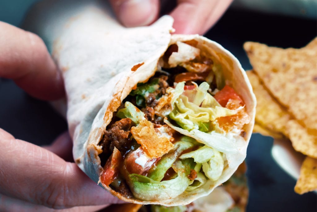 Man holding a burrito as camping food