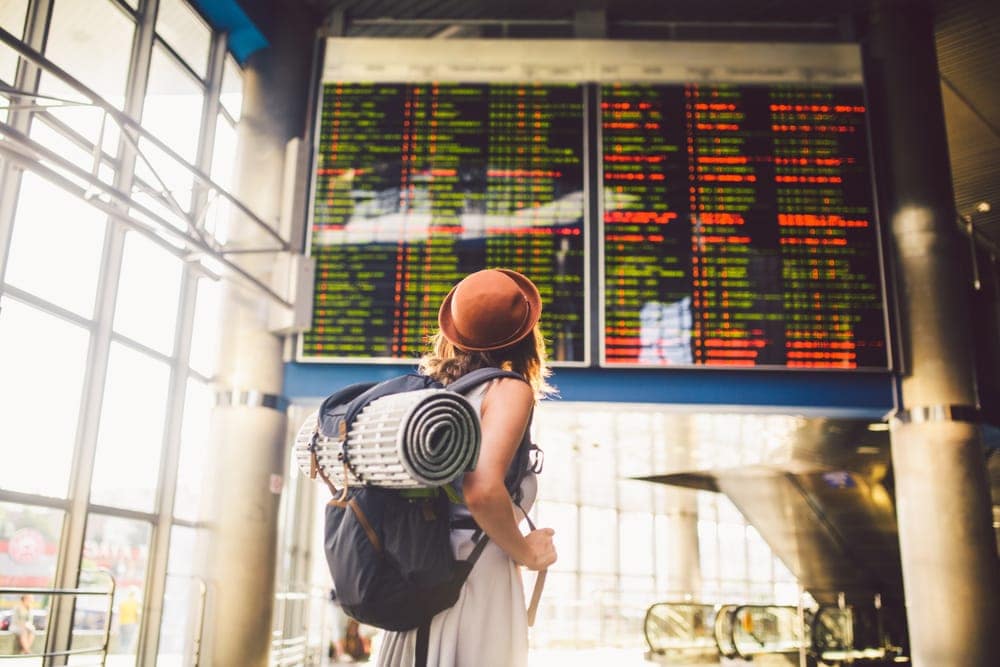 Woman carrying a backpack with camping gears checking her flight