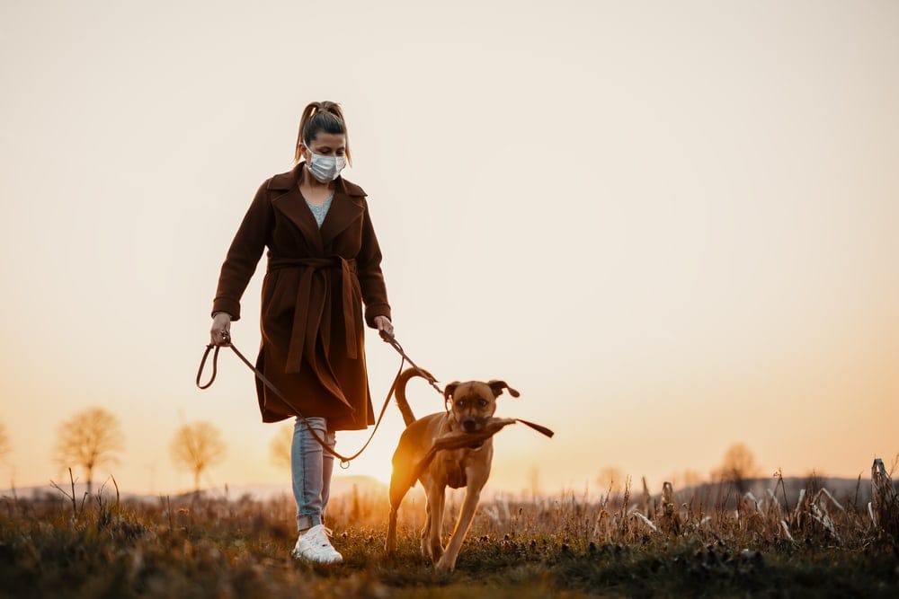 A woman holding the leash of her dog while hiking