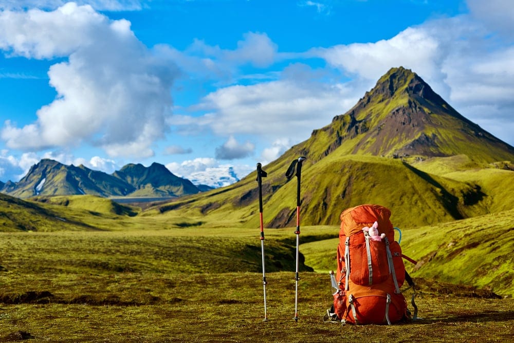 Backpack and a trekking pole with mountain at the back