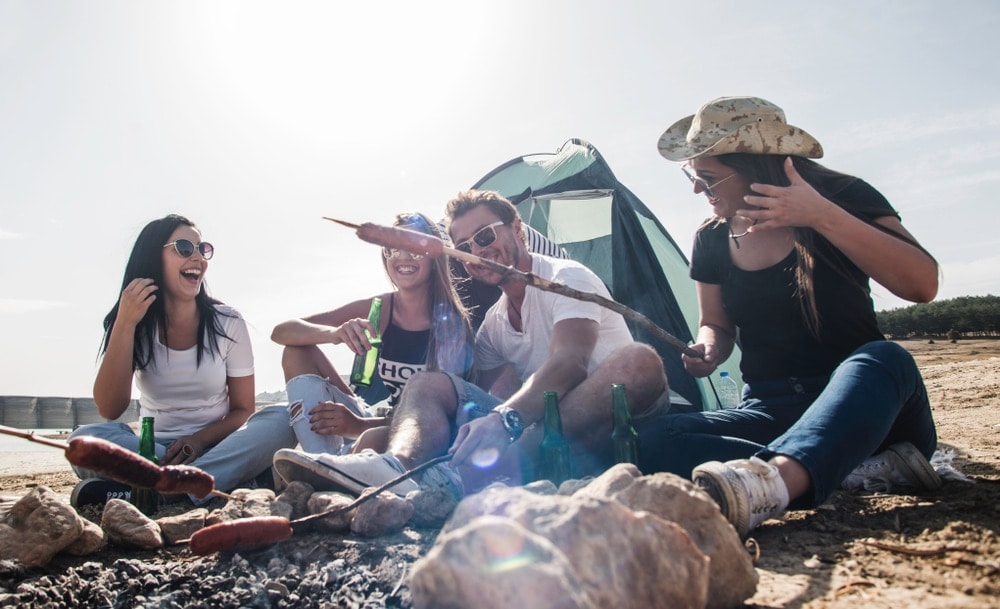 Friends smiling and laughing while cooking and playing camping games