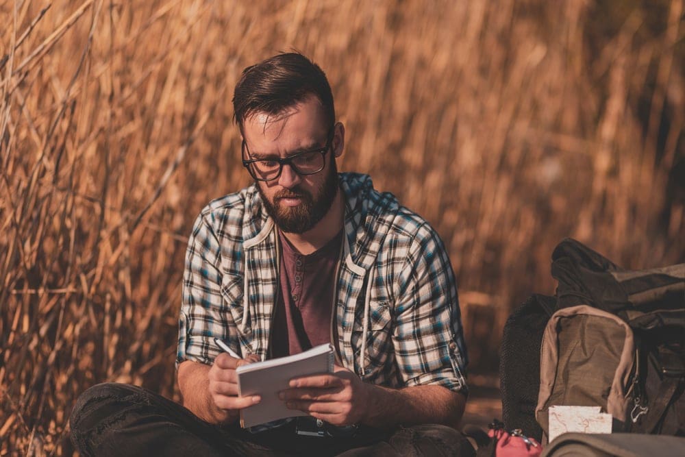 Man writing on a journal as part of a camping game