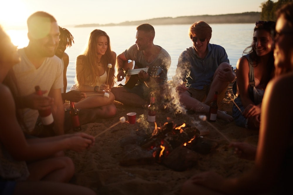 Group of friends drinking, singing and playing campfire games