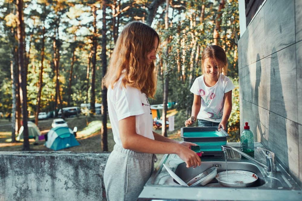 Kids washing dishes in the campground to keep