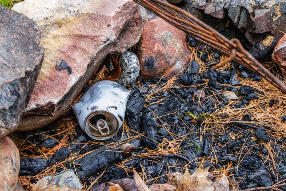 Burned drink cans under big rocks