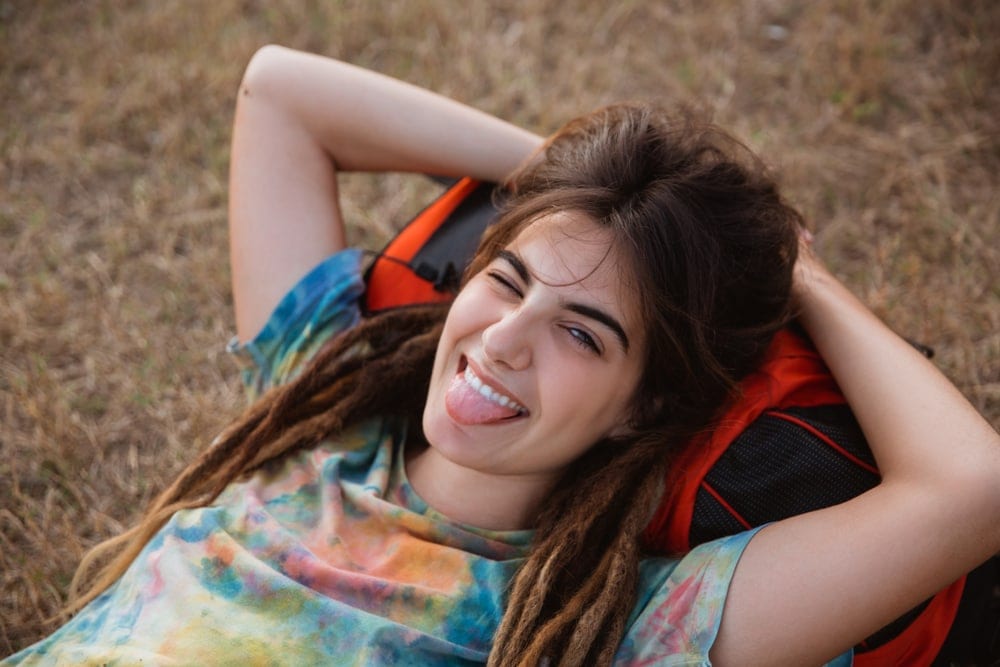 Woman winking while lying on the grass as part of a campfire game