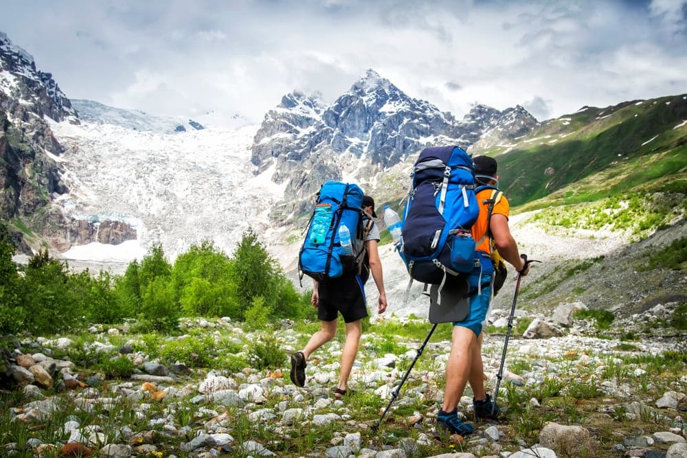 Two hikers with large backpacks in mountains. 