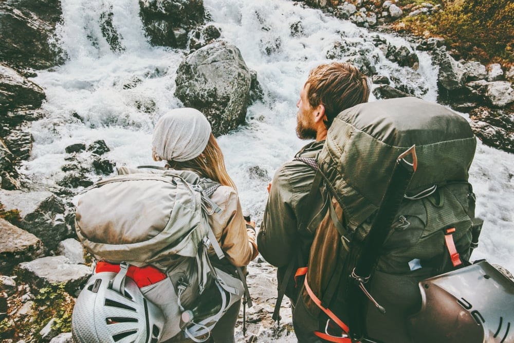 Couple with backpacks into the wild mountains