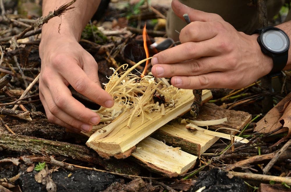 Man trying to light a fire using a fire starter