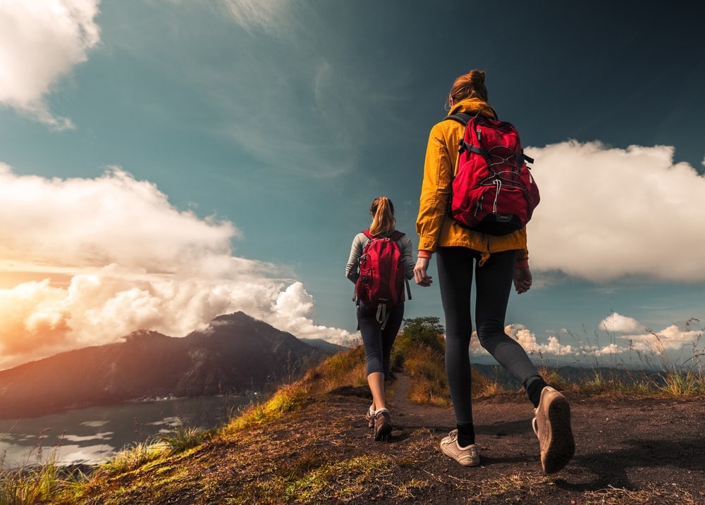 Two hiking buddies wearing backpacks going on a lake