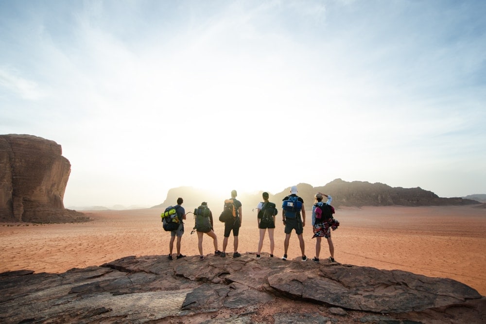 Hiking group on top of a mountain in a desert enjoying the view