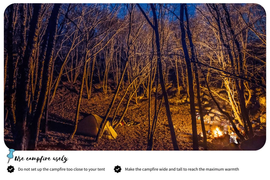 Camping tent in front of a campfire in the middle of the forest