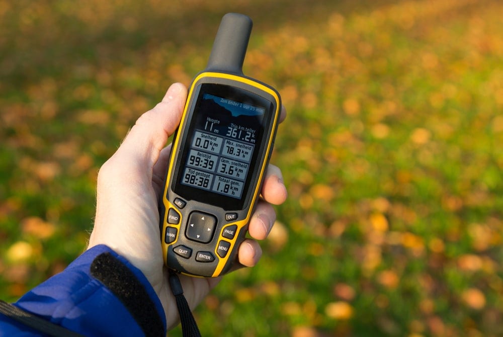 Person's hand holding a handheld gps for hiking