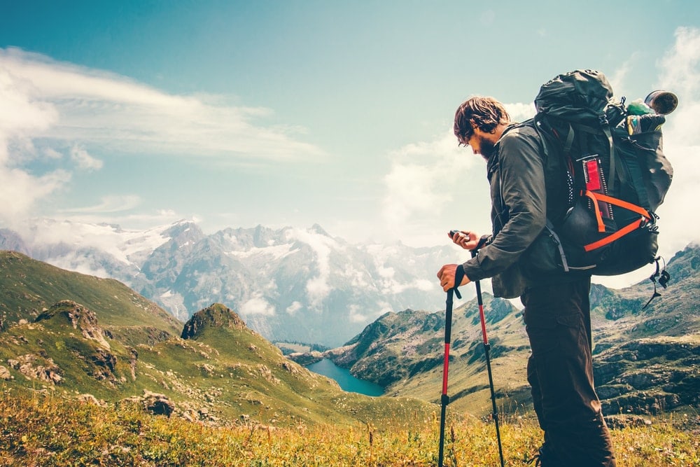 Hiker with a big backpacking backpack holding a handheld portable gps