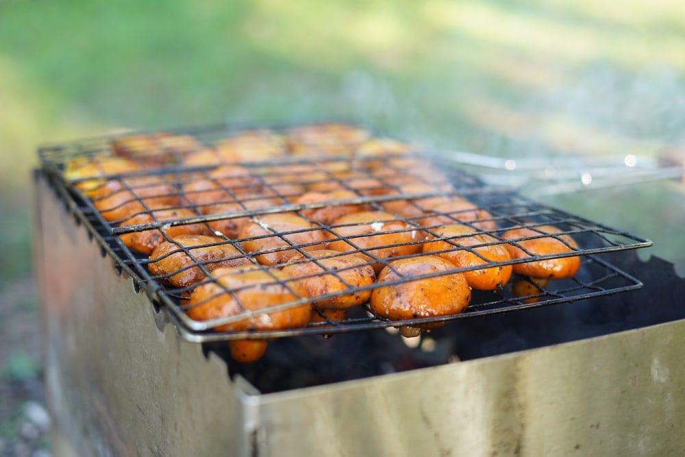 Mushrooms  being cooked in a camping basket grill