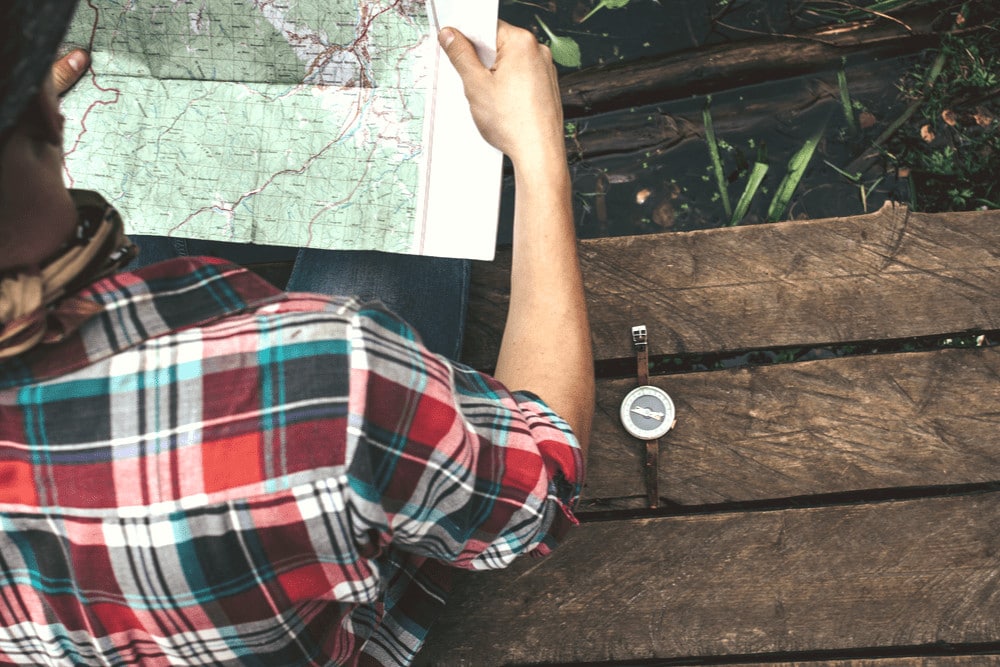 Man holding a map and a compass on a wood chair