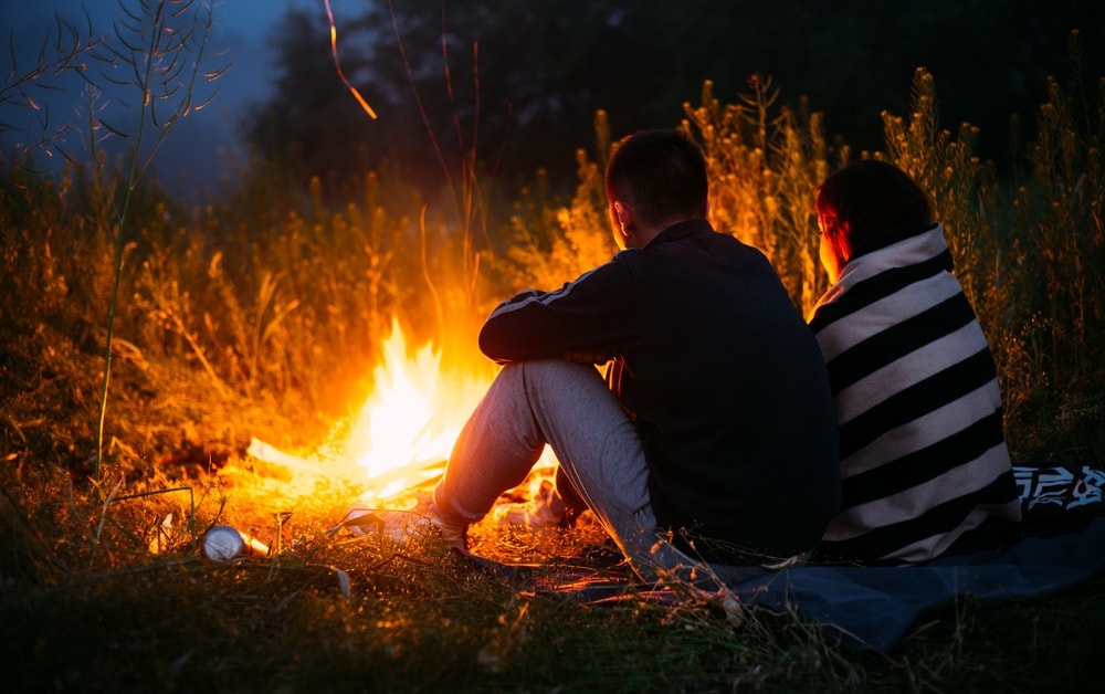 Couple near a fire at the end of hiking date