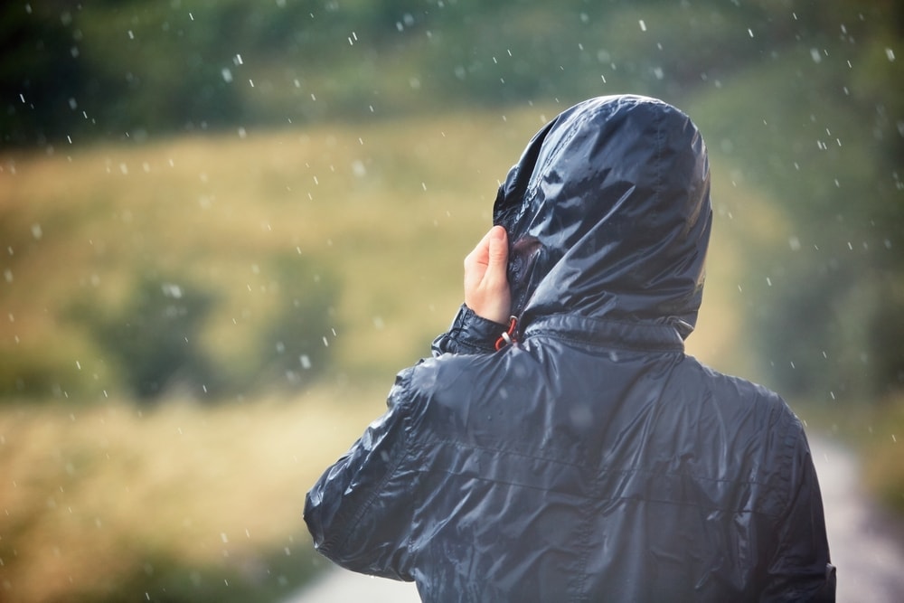 Hiker holding a hiking jacket during a rain