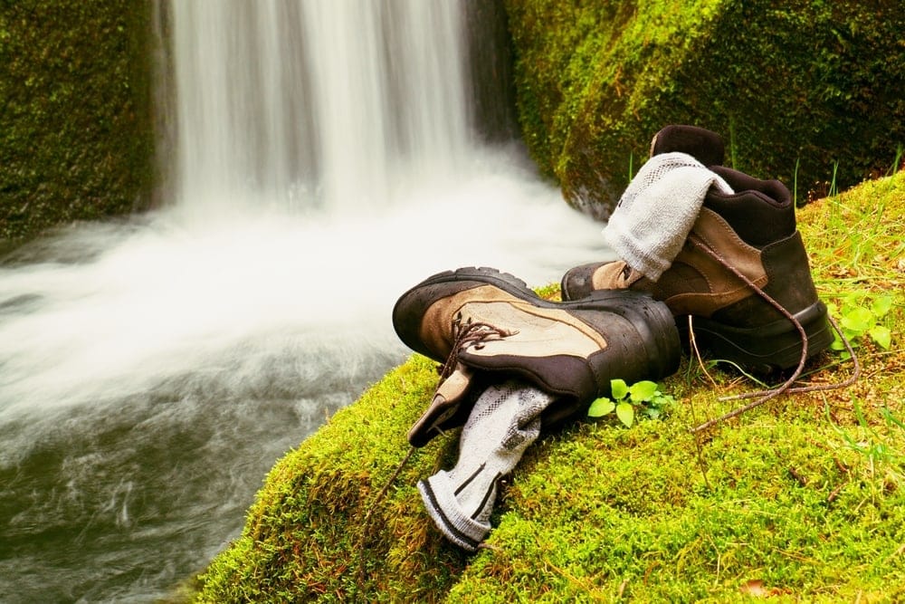A pair of  hiking socks in the shoes facing a waterfall