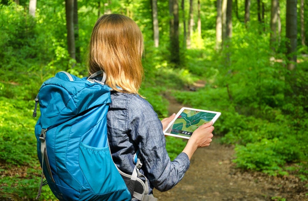 A woman holding a large screen GPS for navigation while hiking