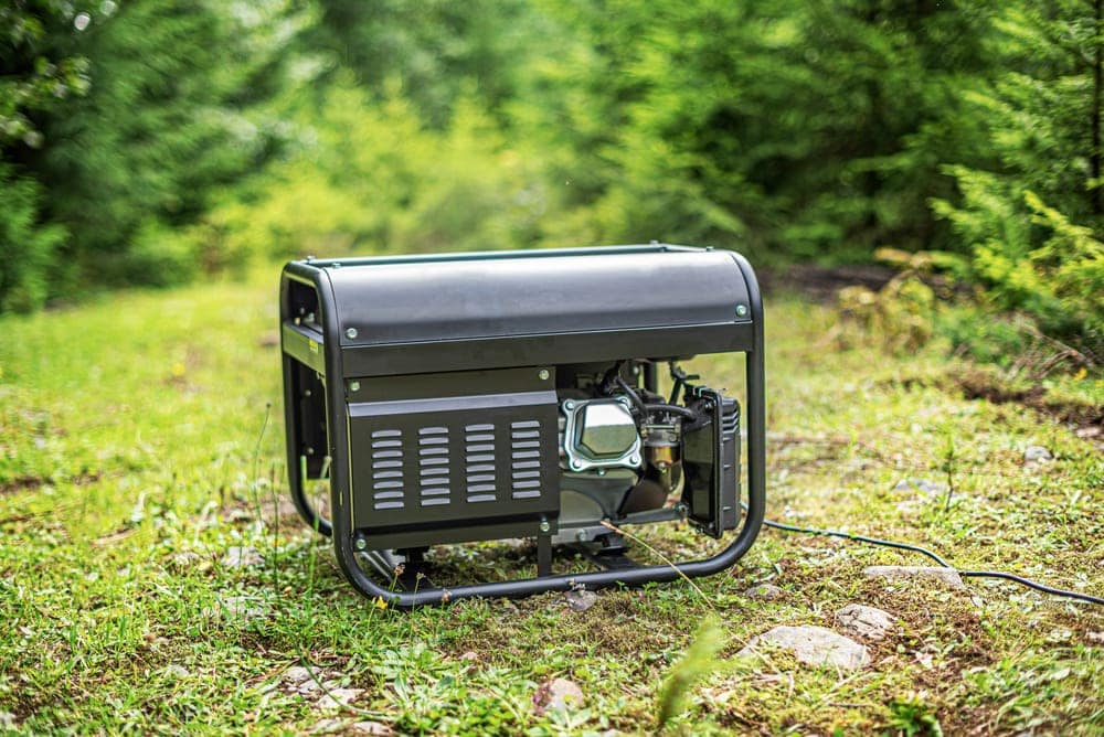 Black portable generator grounded for camping on the grass