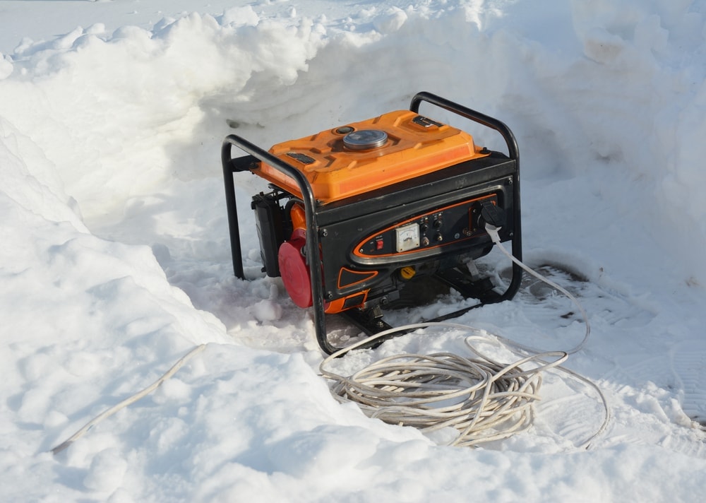 Generator on a snowy ground with a long coiled wire beside it
