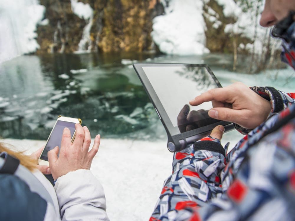 Man and woman holding their gadgets while searching for internet while camping