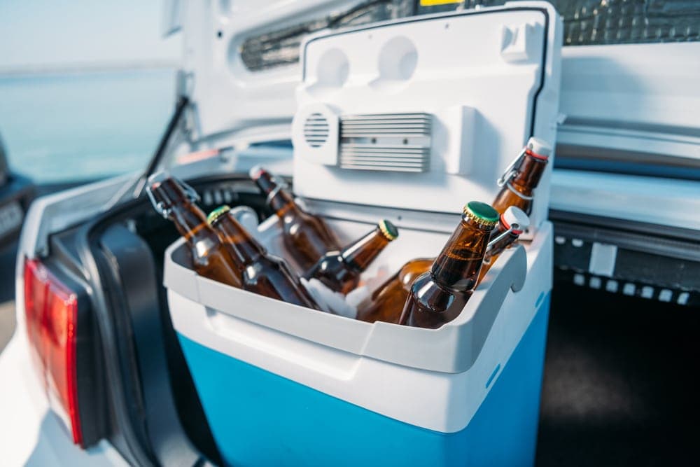Cooler in a car trunk filled with drinks and dry ice for camping