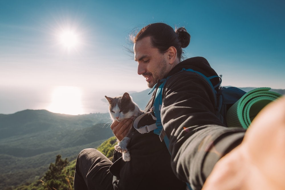 Man holding a cat on a backpacking trip