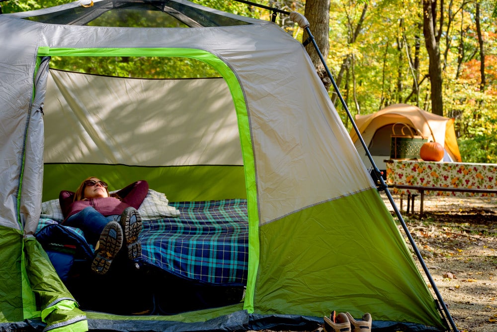 A woman lying down on a camping cot inside a tent
