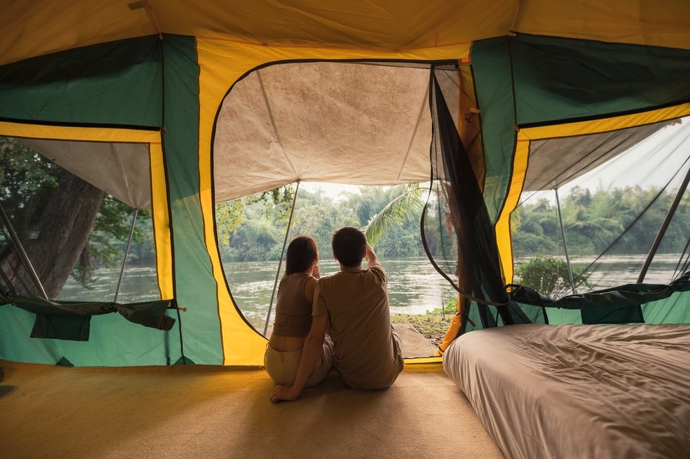Couple sitting and talking near an air mattress inside a big tent